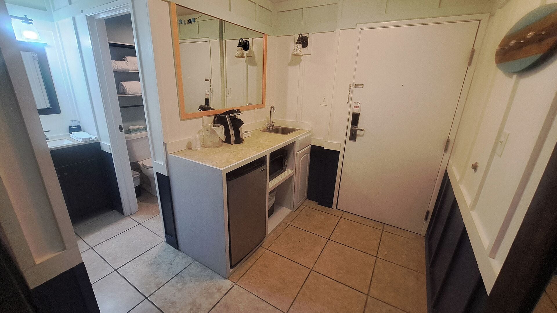 A compact bathroom with a sink, mirror, and toilet.