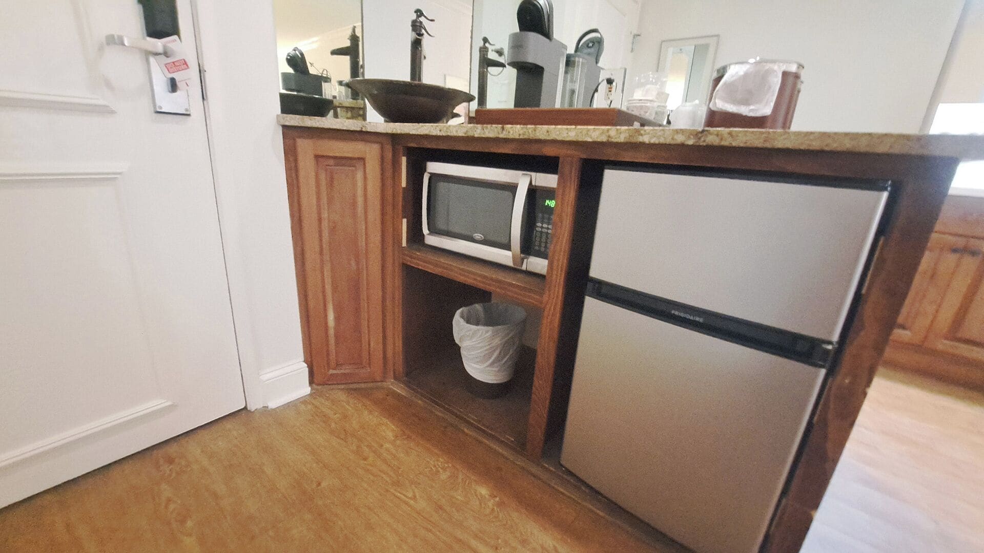 A compact kitchen with a microwave, refrigerator, and wooden cabinets.