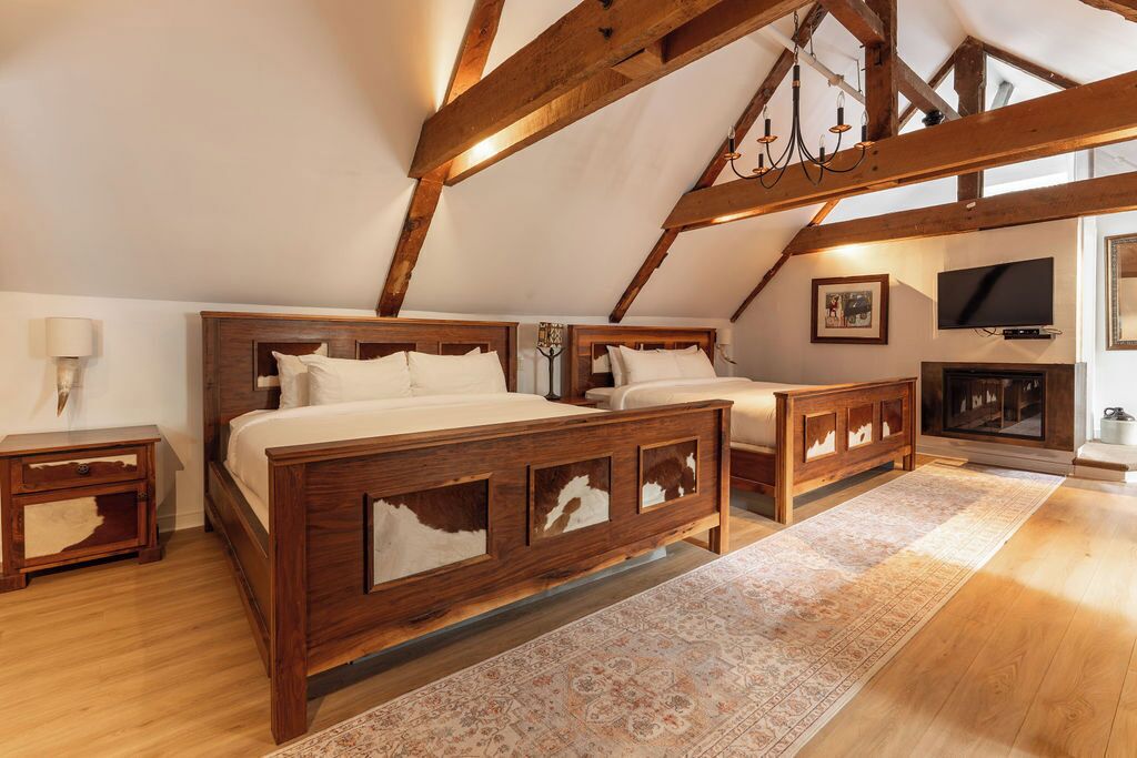 A bedroom with two wooden beds, a television, and a fireplace.