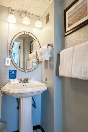 Une salle de bain avec un lavabo, un miroir et un porte-serviettes.