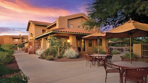 A courtyard with outdoor seating, a stone pathway, and a building with a tiled roof. - WorldMark Rancho Vistoso (Oro Valley)
