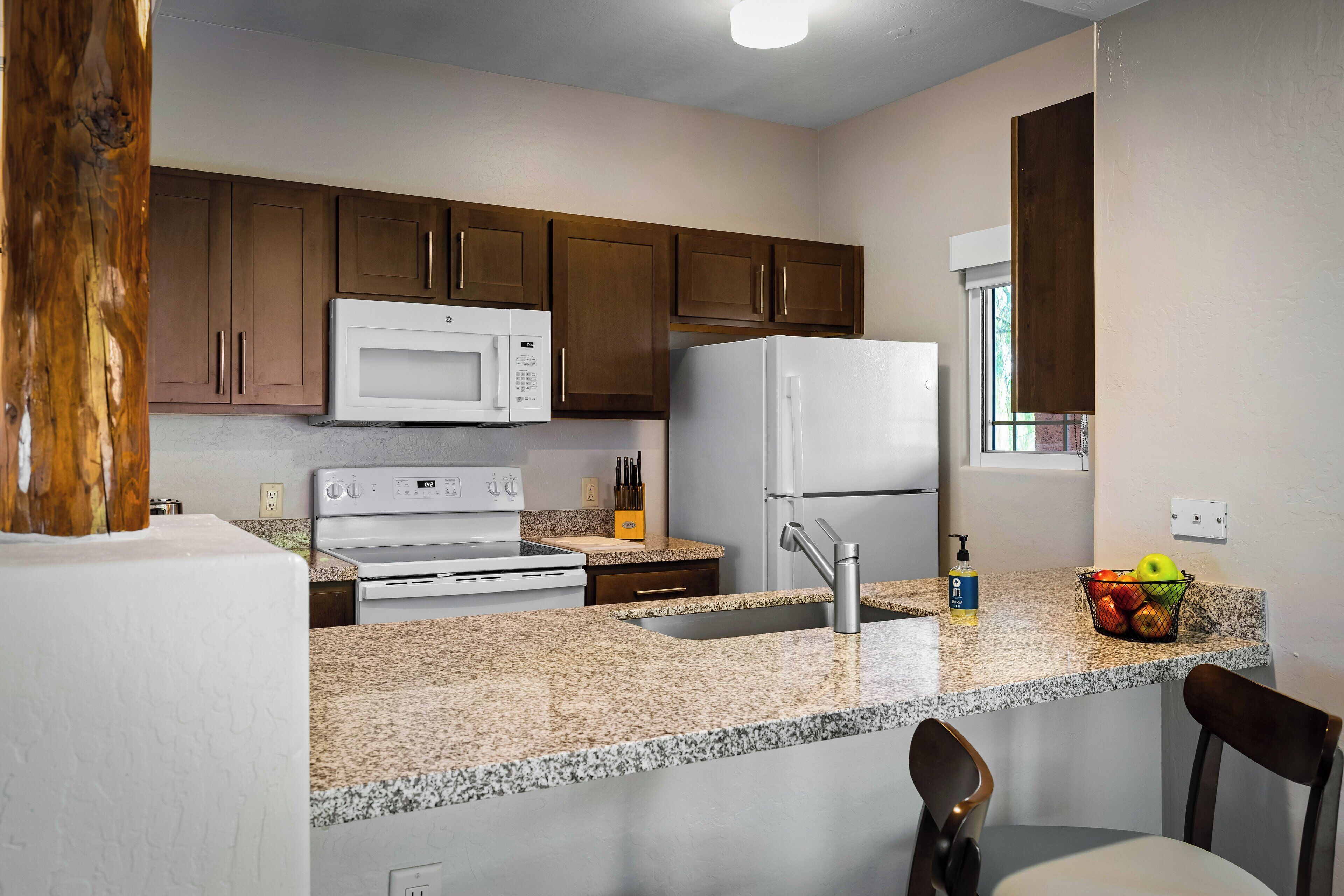 Eine moderne Küche mit Granit-Arbeitsplatten, Edelstahlgeräten und Holzschränken.