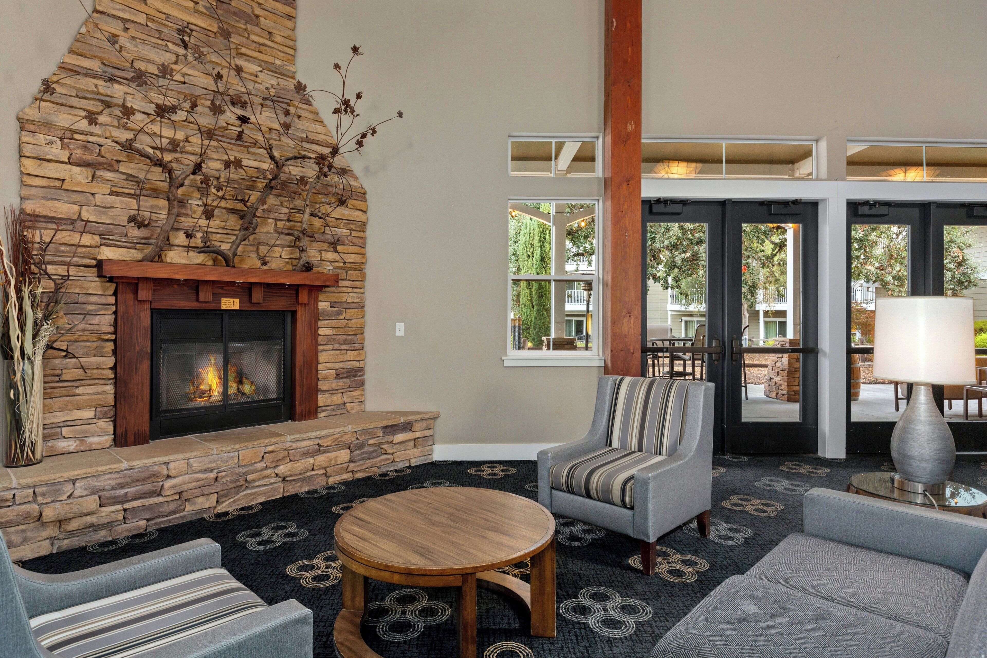 A cozy interior with a stone fireplace, comfortable seating, and a view through large windows.
