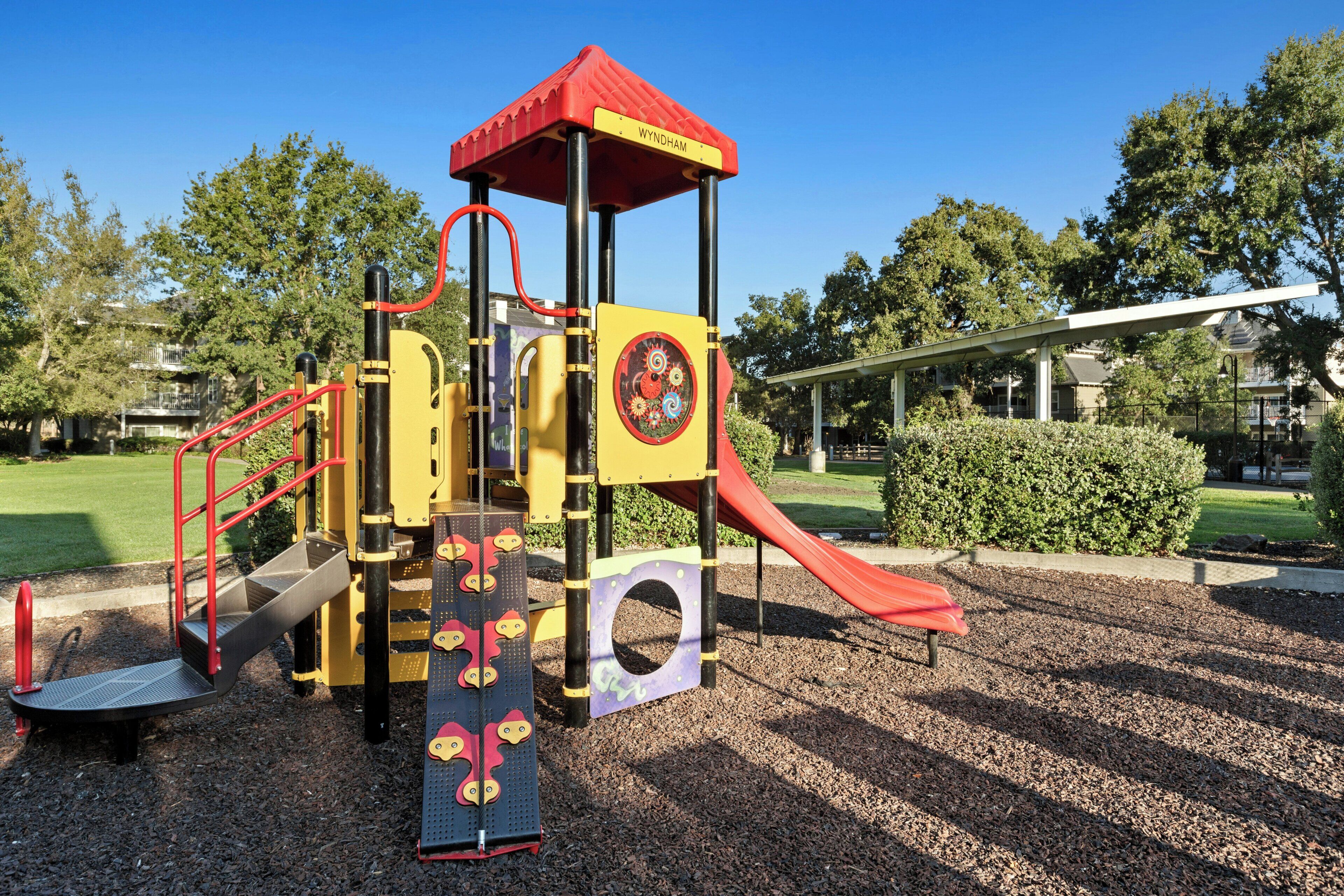 A playground with a red slide and climbing structures.