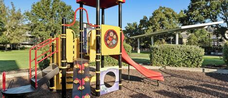 A playground with a red slide and climbing structures.
