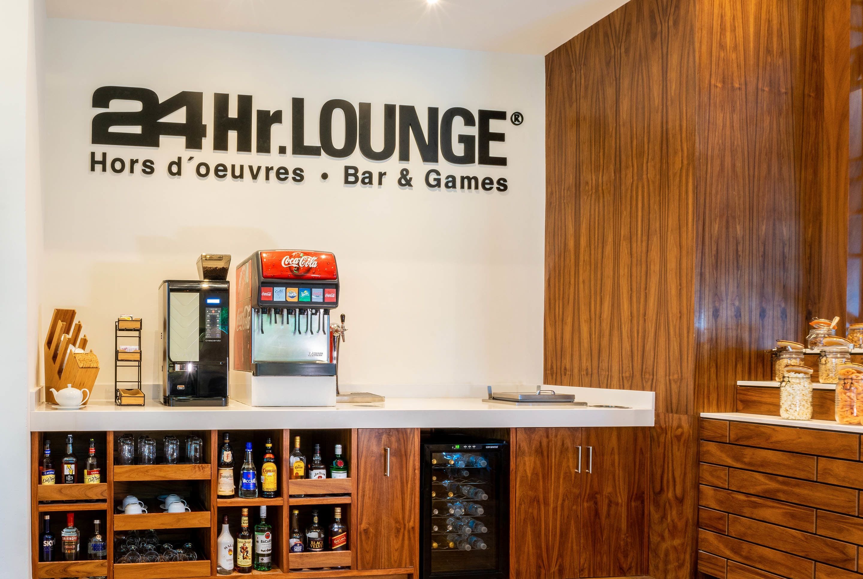 Un espace de détente ouvert 24 heures sur 24, équipé d’un distributeur de Coca-Cola, d’un réfrigérateur et d’étagères remplies de boissons.