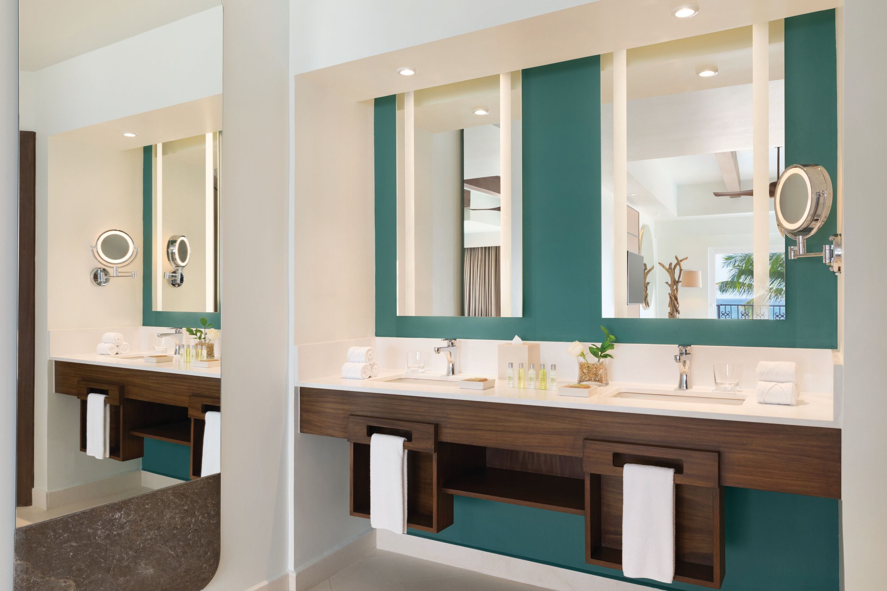 A modern bathroom with two sinks, a large mirror, and a vanity with a towel rack.