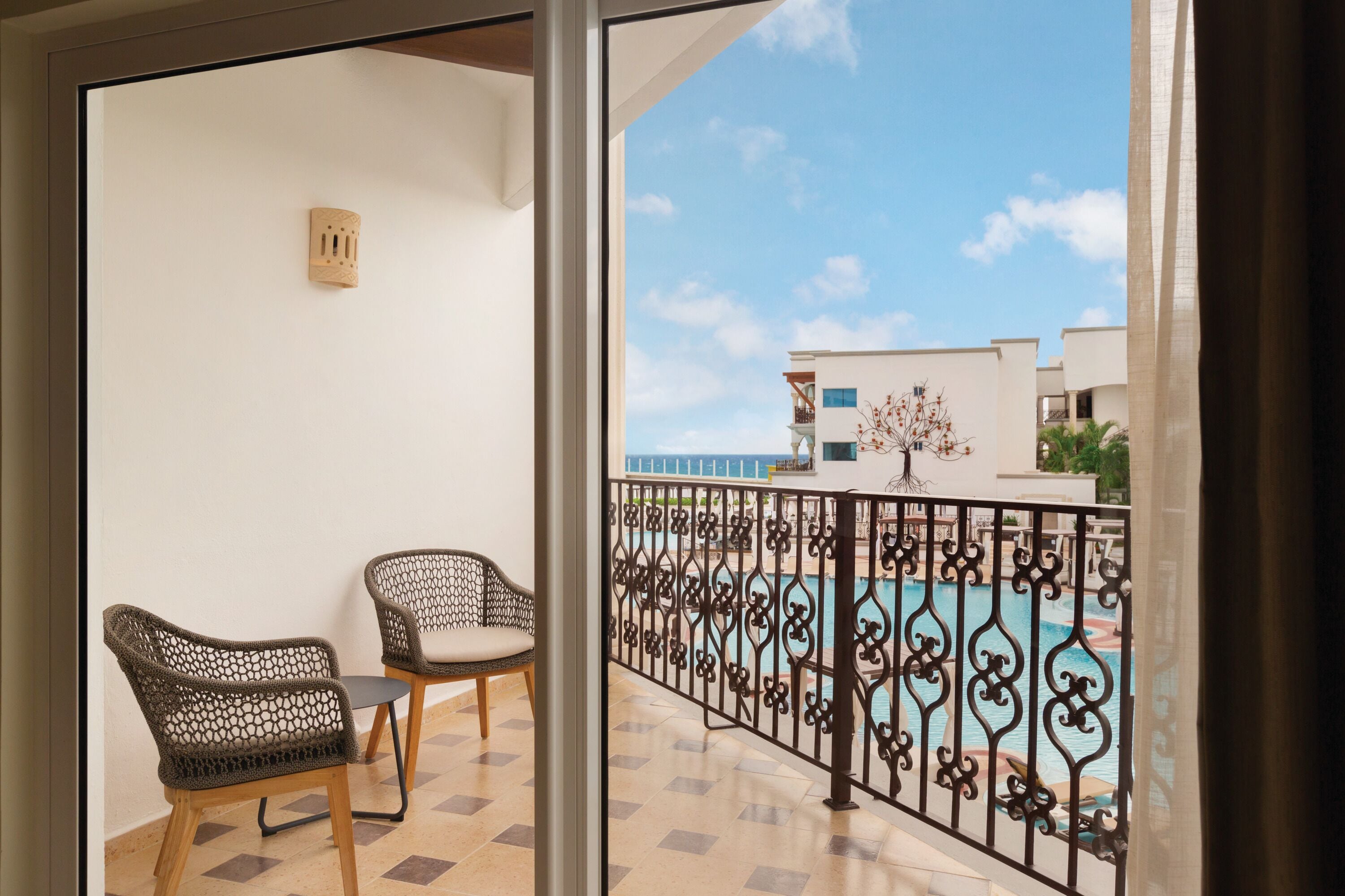 Un balcon agrémenté de deux fauteuils en osier, d’une petite table et d’une rambarde décorative en métal.