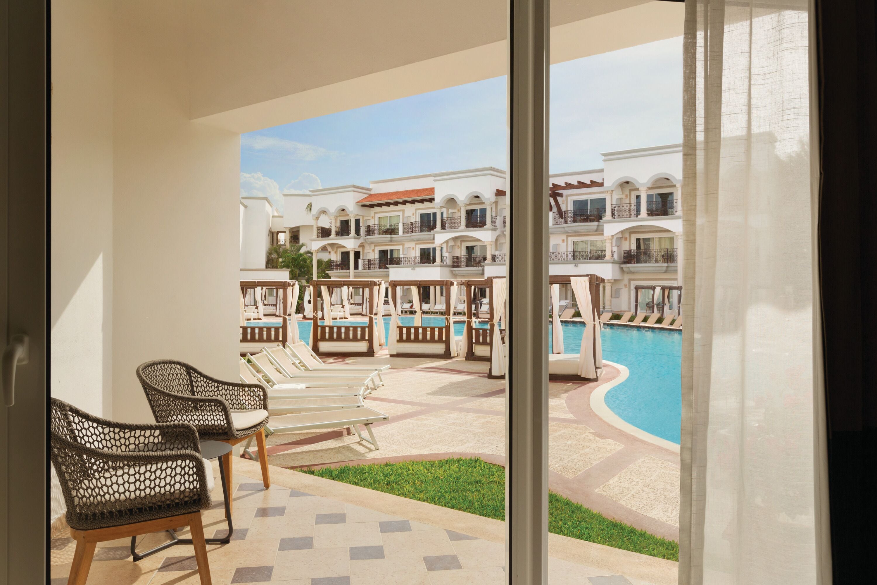 Un balcón con sillones de descanso y una zona de piscina, con vistas a un edificio de varios pisos con balcones.