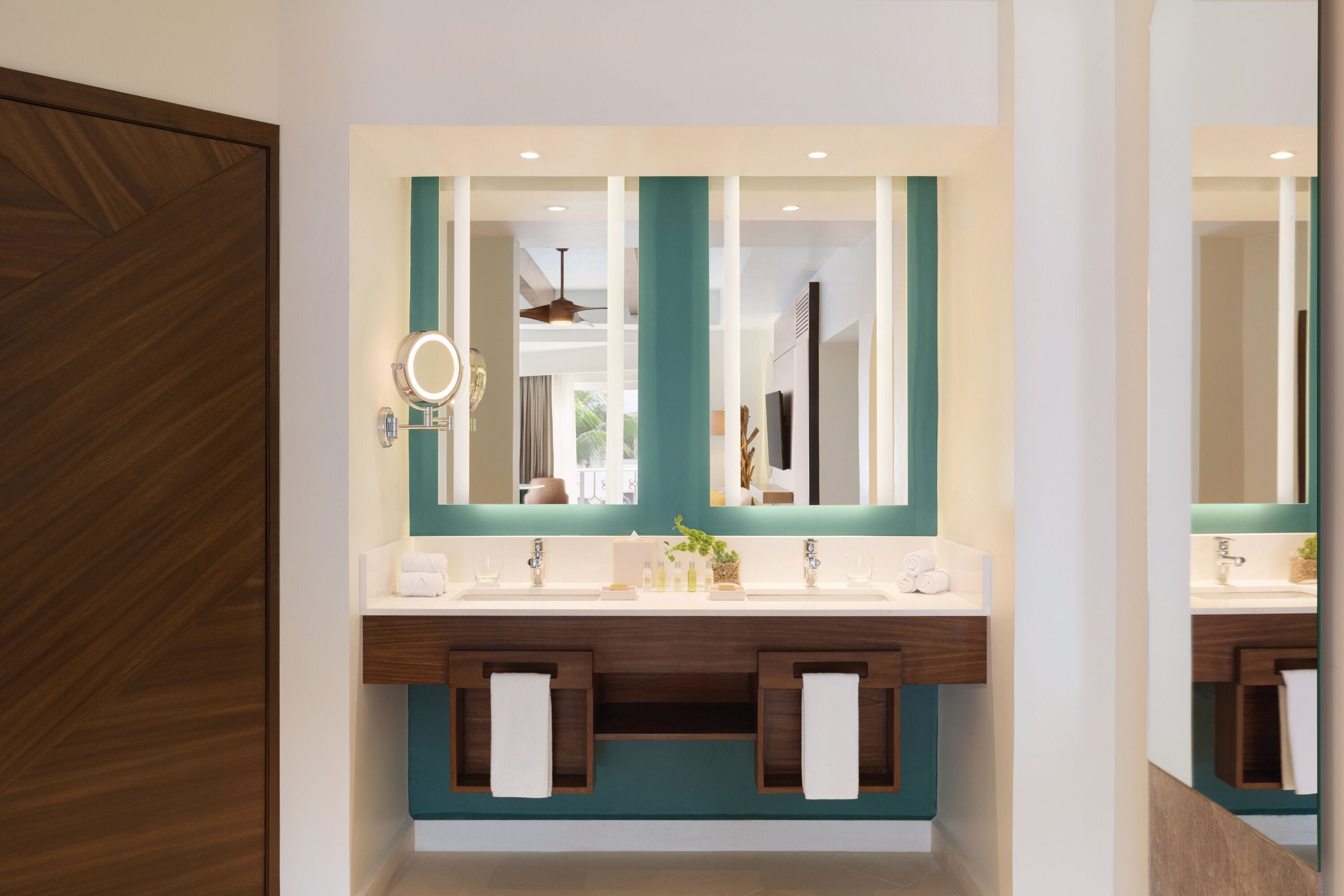 Un baño moderno con un espejo grande, dos lavamanos y armarios de madera.