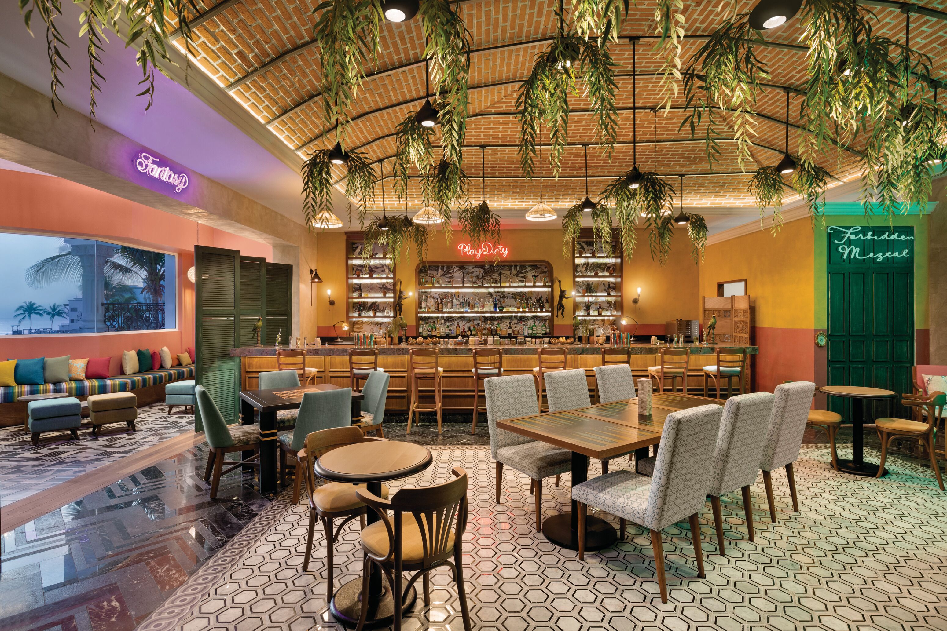 Un restaurante con barra, distribución de mesas y plantas colgantes.