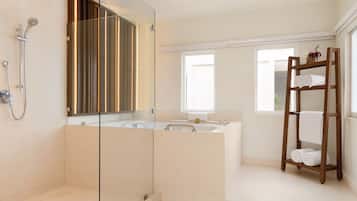 A modern bathroom with a glass-enclosed shower, a large bathtub, and a wooden towel rack.