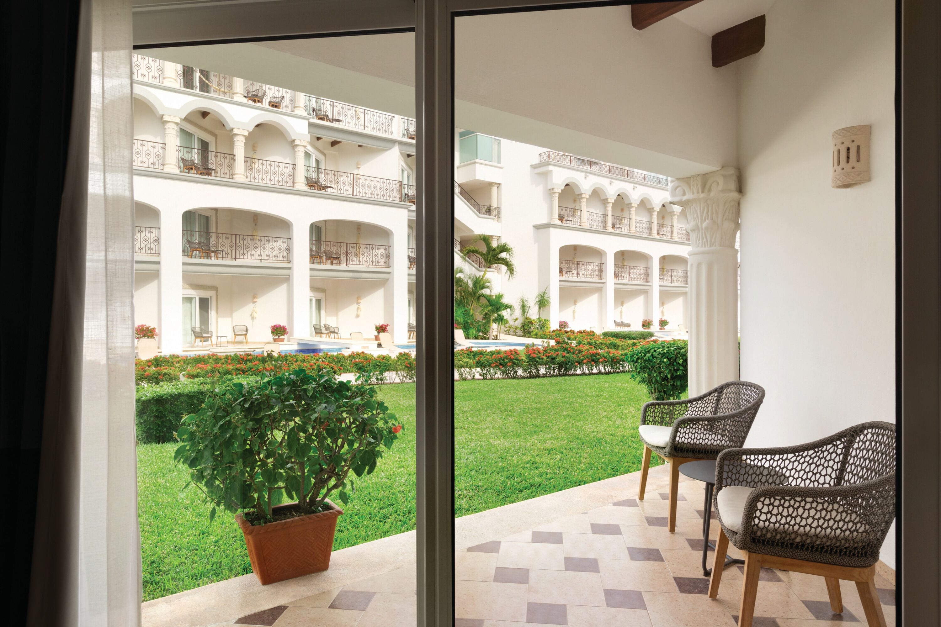 A hotel courtyard with a pool, multiple balconies, and outdoor seating.