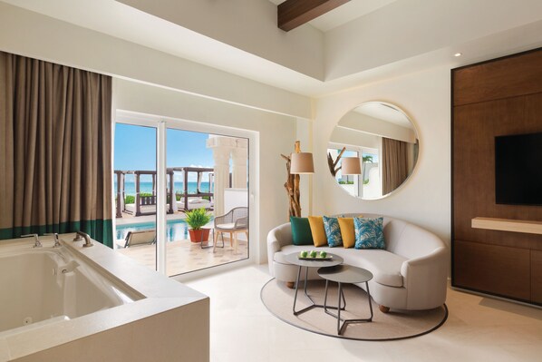 A modern hotel room with a large bathtub, a sofa with colorful cushions, a round coffee table, and a TV mounted on the wall. - Hyatt Vivid Playa Del Carmen - Adults Only - All Inclusive                                                                    (Playa del Carmen)