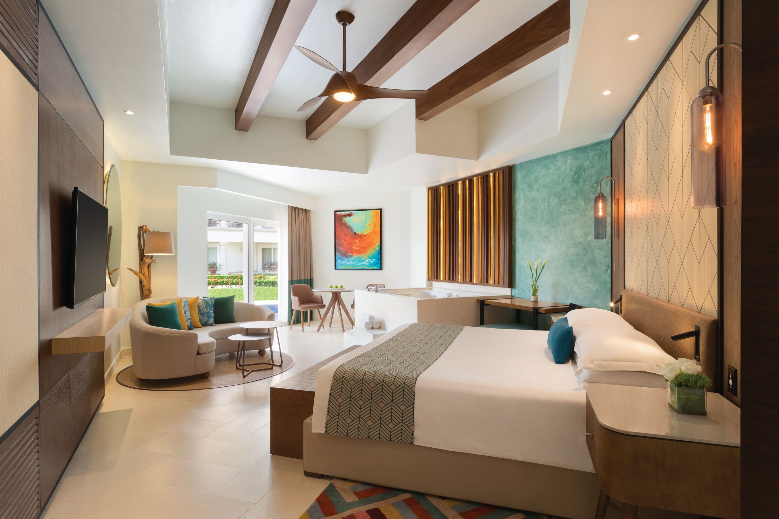 A modern hotel room with a large bed, a desk, a sofa, and a TV.
