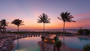 A poolside area with lounge chairs and palm trees, overlooking the ocean at sunset. - Hyatt Vivid Playa Del Carmen - Adults Only - All Inclusive                                                                    (Playa del Carmen)
