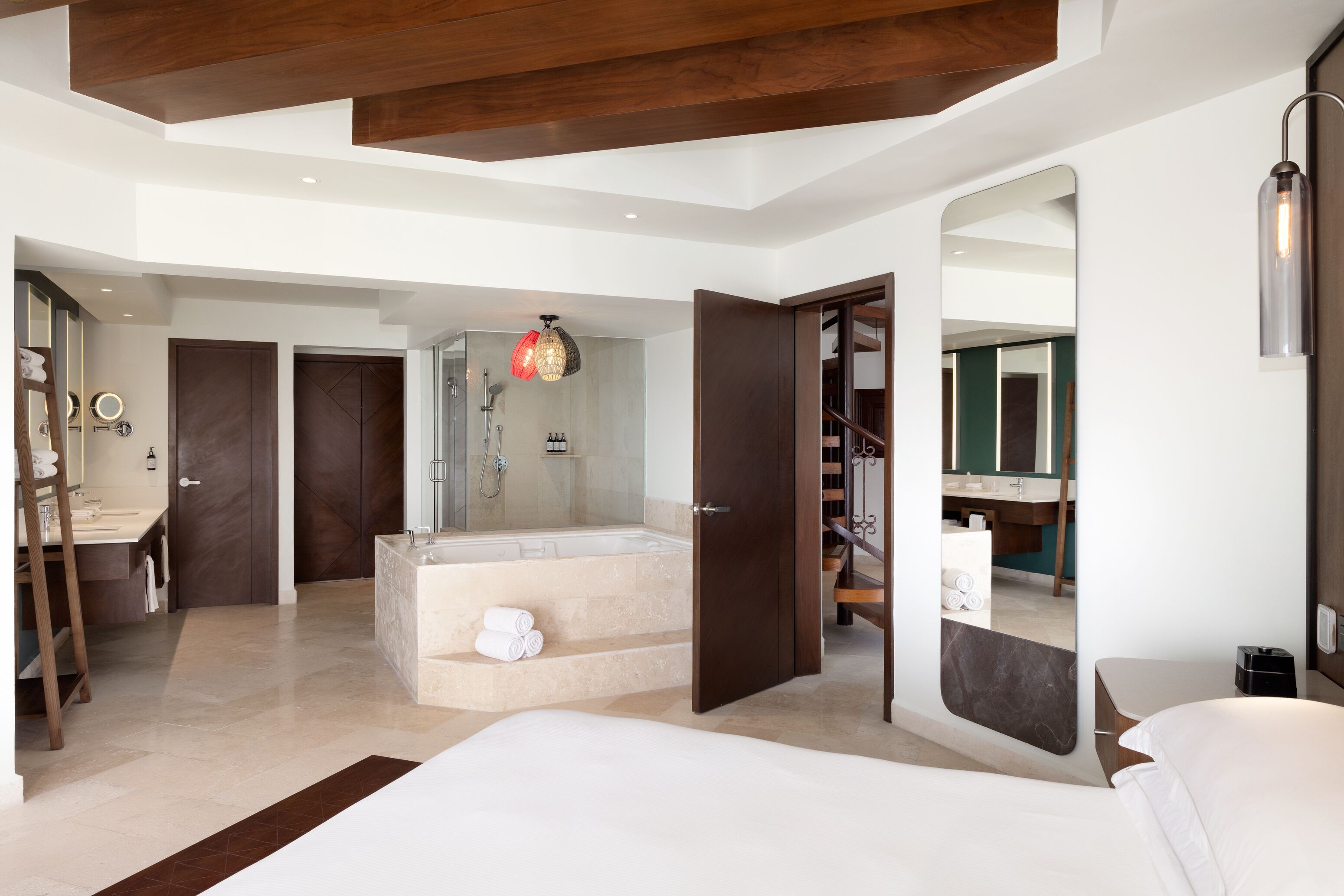 A modern bedroom with a large bed, a walk-in closet, a bathroom with a bathtub, and a shower.