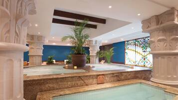 Un espacio de spa con piscina, columnas y una planta grande en maceta.