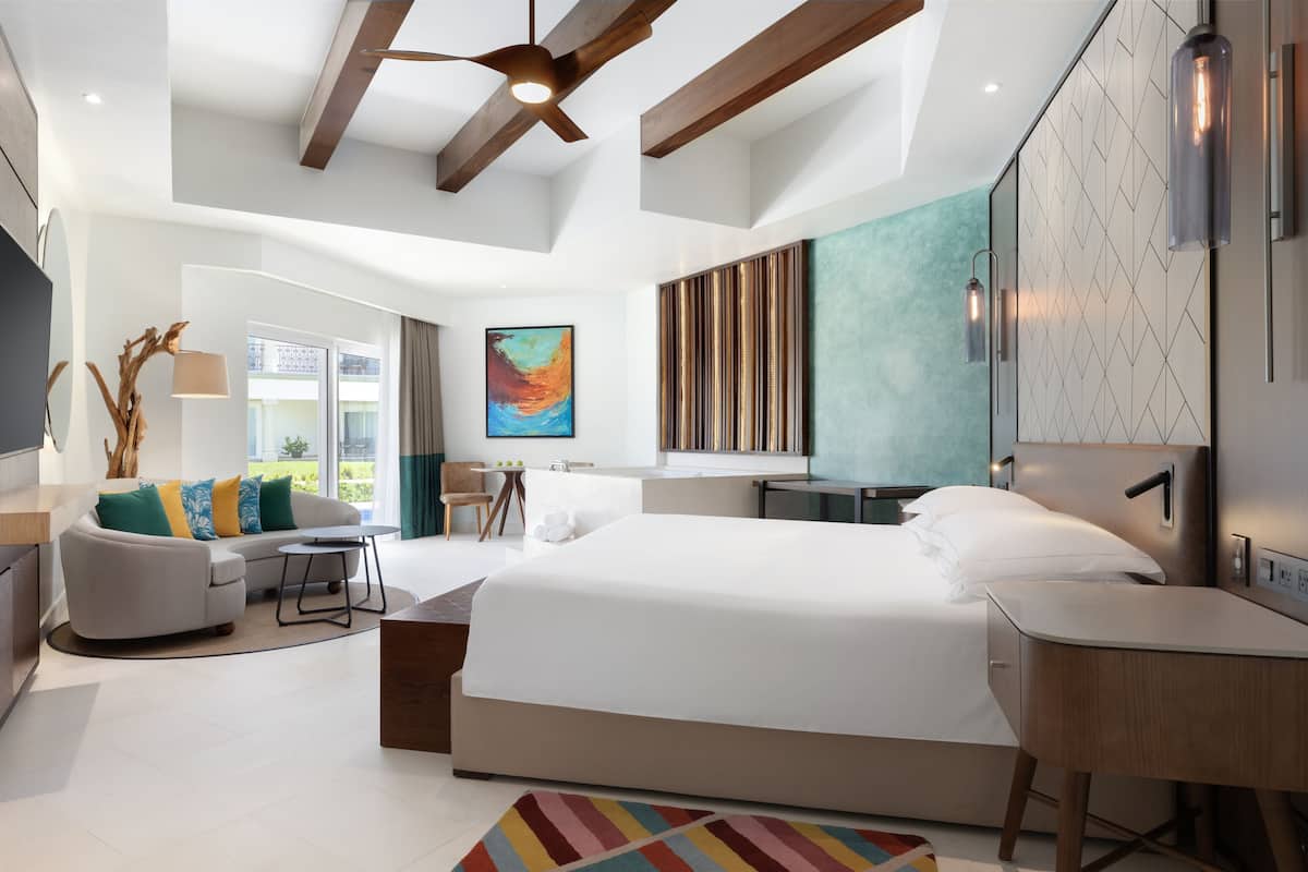 Una habitación de hotel moderna con una cama grande, un escritorio, un sofá y vistas al exterior.
