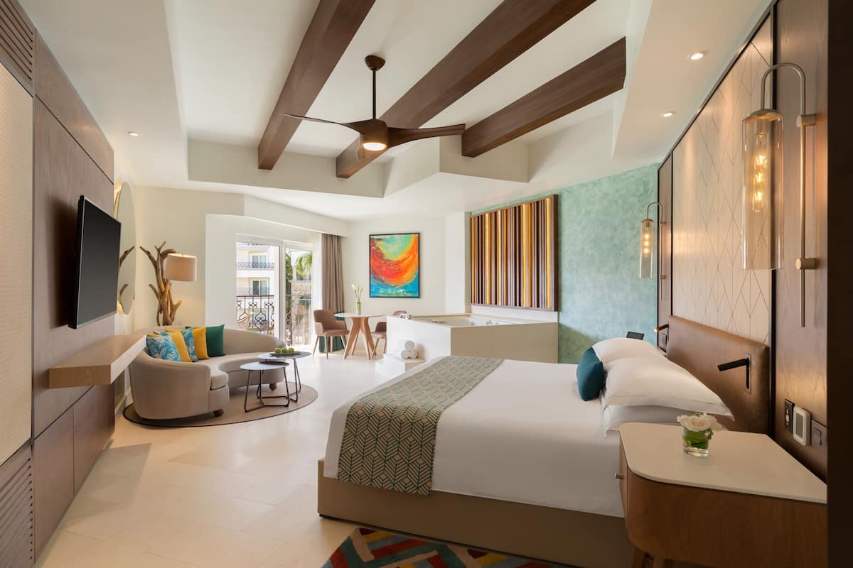 Una habitación de hotel moderna con una cama grande, un sofá, un escritorio y vistas al exterior.