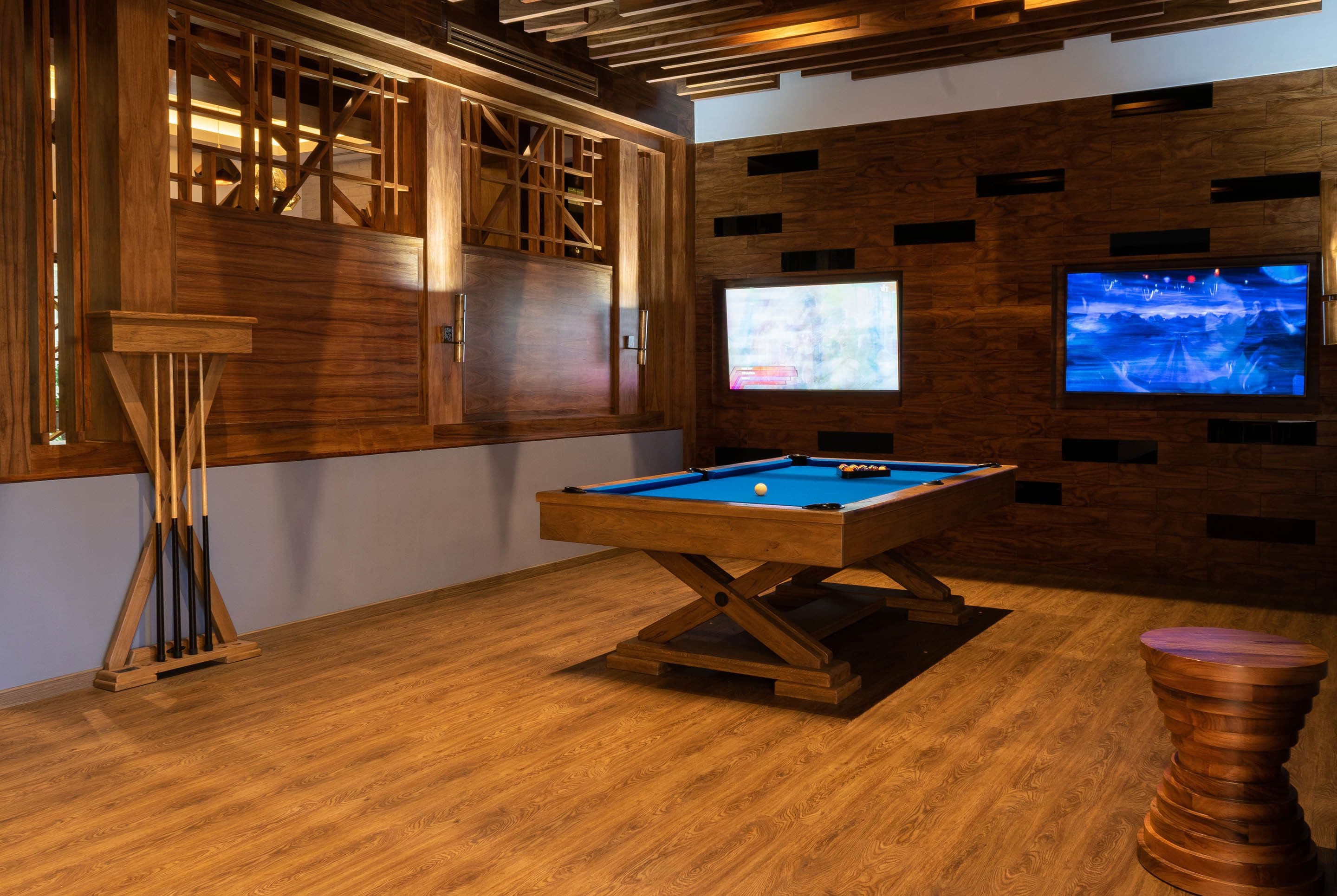 A pool table in a room with wooden paneling and a television mounted on the wall.