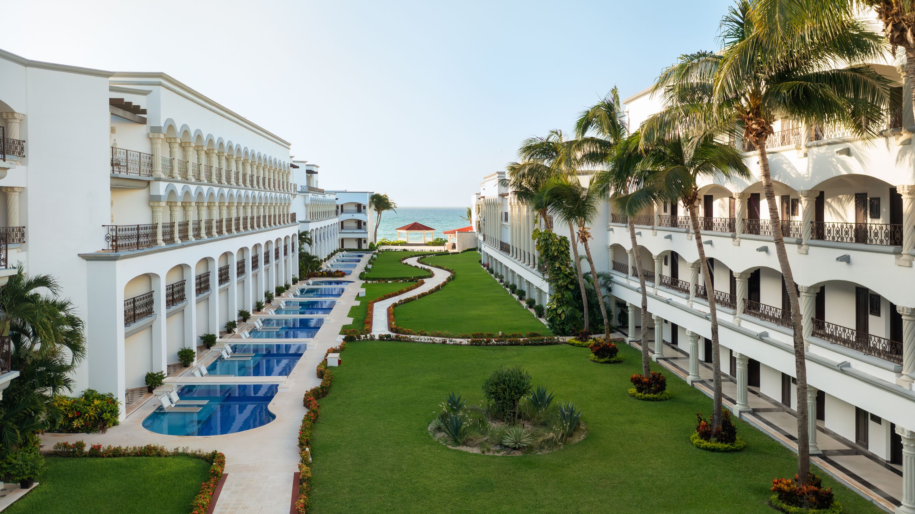 Un resort con varias piscinas, un césped bien cuidado y vista al océano.