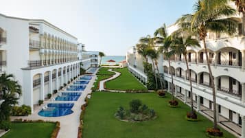 Un resort con varias piscinas, un césped bien cuidado y vista al océano.
