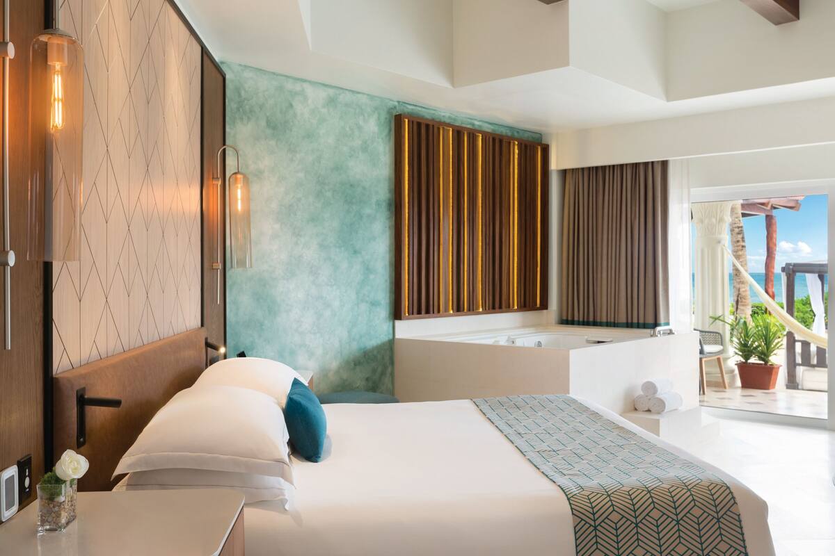 Una habitación de hotel moderna con una cama grande, una bañera y vistas al mar.