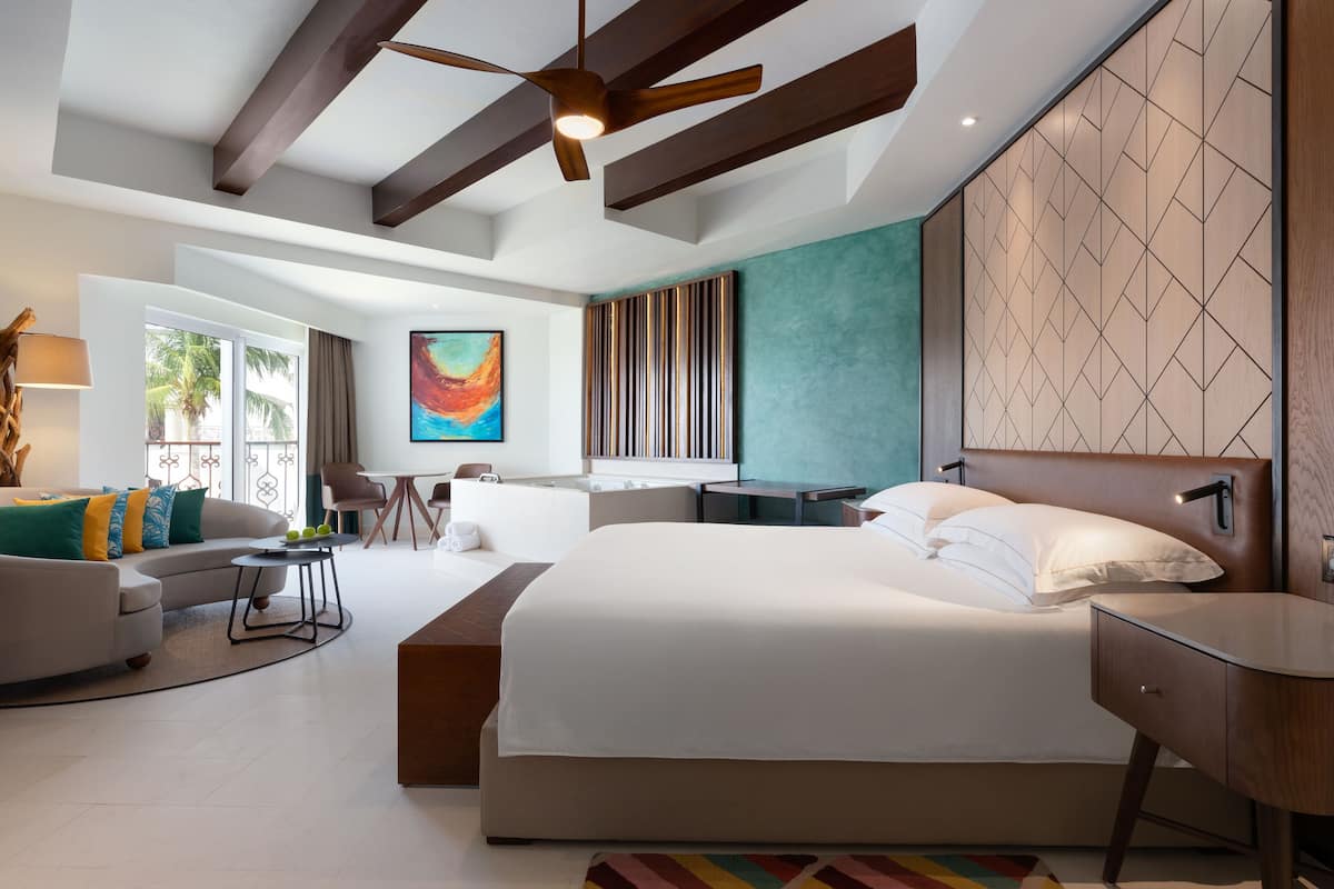 Una habitación de hotel moderna con una cama grande, un escritorio, un sofá y una zona de comedor.
