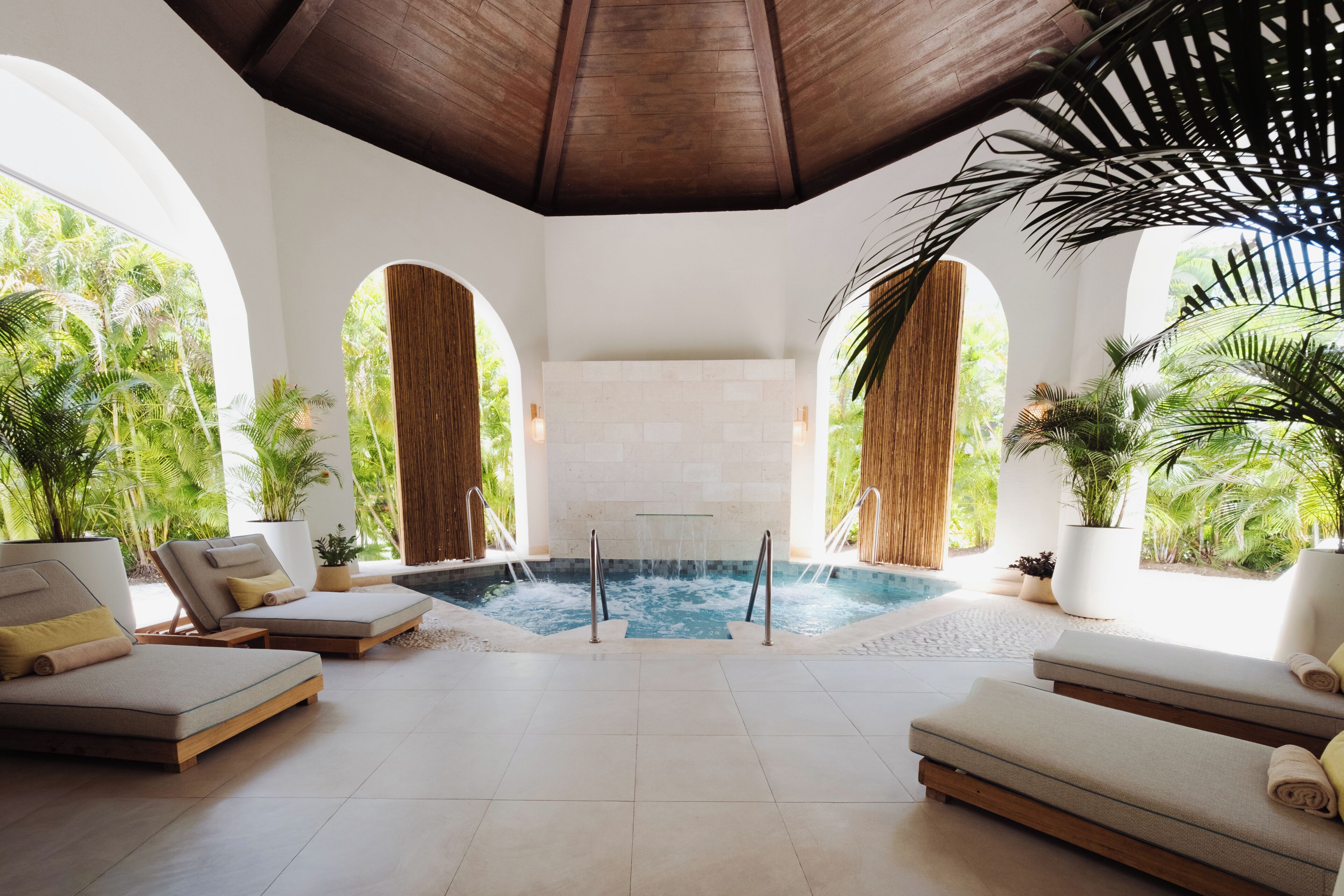 A spa area with a hot tub, lounge chairs, and potted plants.