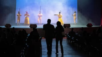 Une scène avec des artistes, un public et un grand écran.