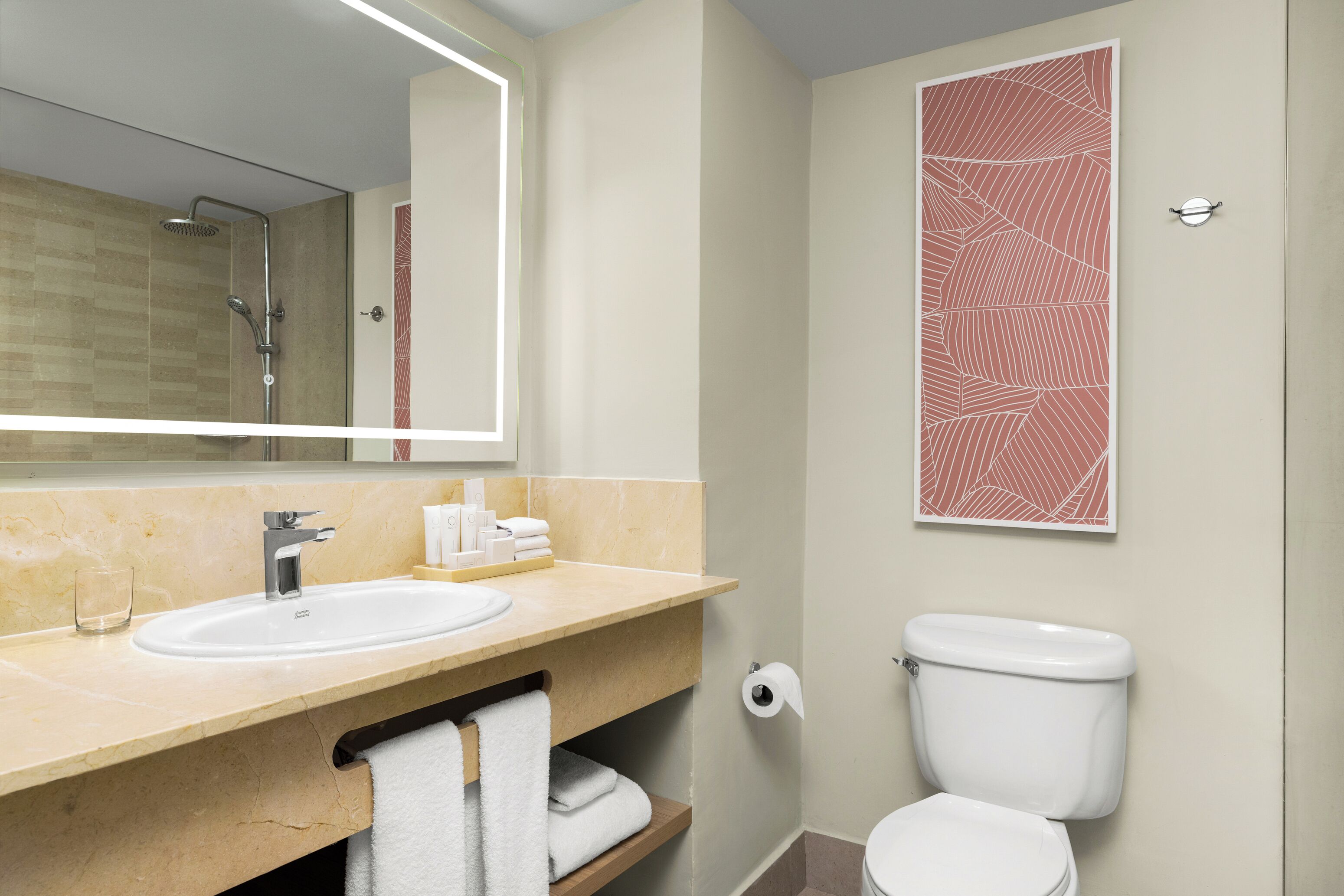 Un bagno moderno con un piano d'appoggio color beige, uno specchio grande, un lavabo, una doccia e un water.