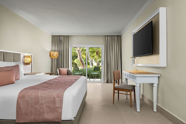 A hotel room with a large bed, a desk, a chair, a television, and a view of the outdoors.