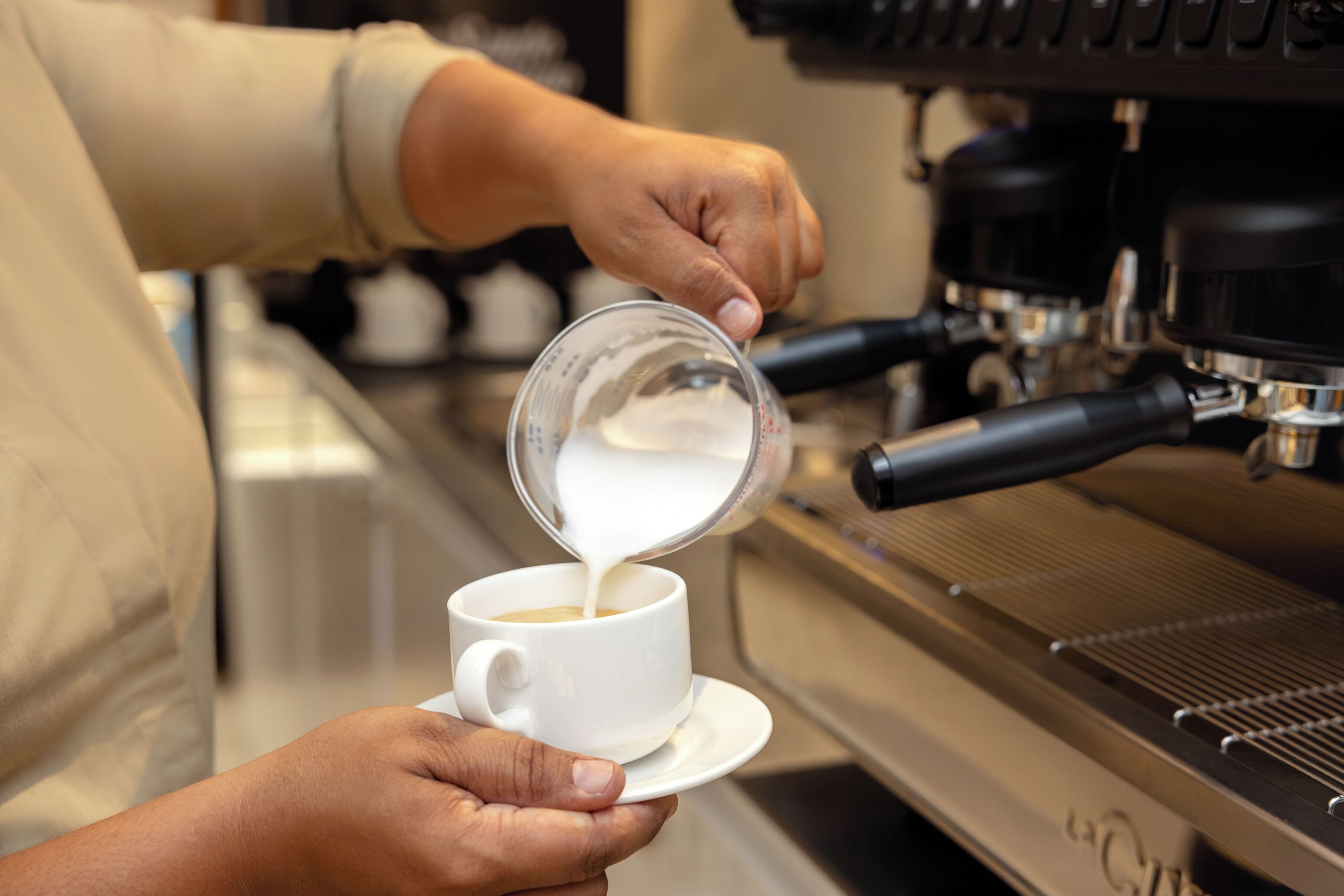 Une personne verse du lait dans une tasse de café.