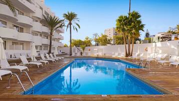 Een buitenzwembad, ligstoelen bij het zwembad