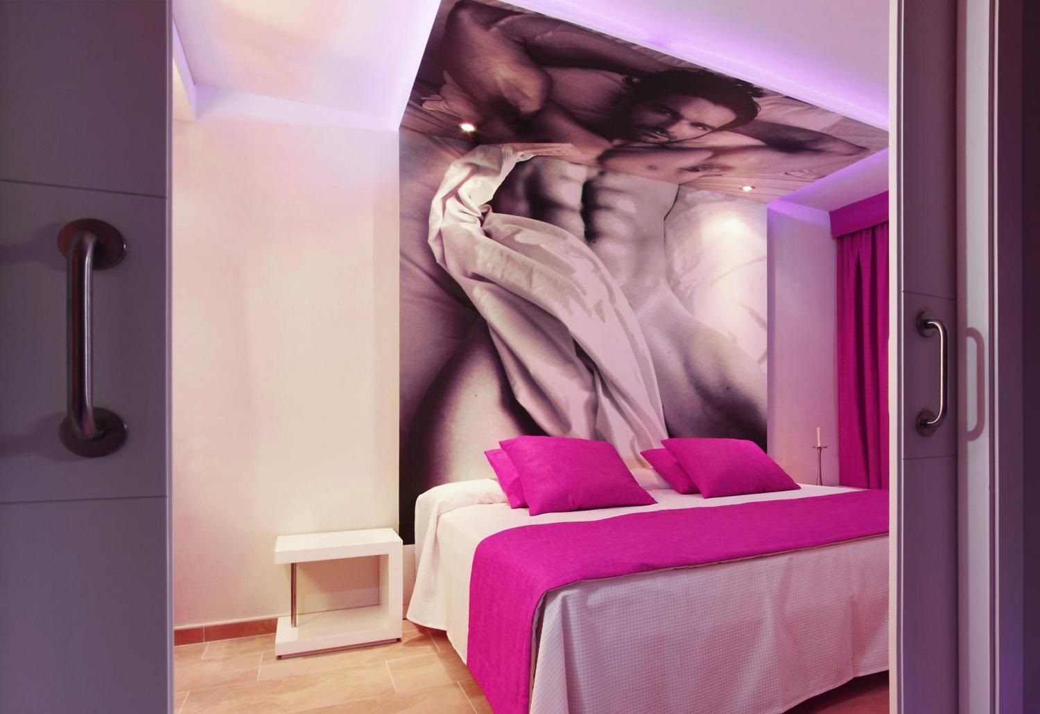Un dormitorio con cama, mesita de noche y un mural en la pared.