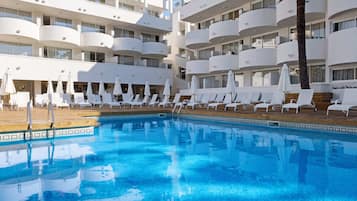 Een buitenzwembad, ligstoelen bij het zwembad