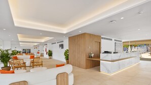 A modern hotel lobby with a reception desk, seating area, and a view of the outdoor pool. - Palmanova Beach Apartments by TRH (Calvia)
