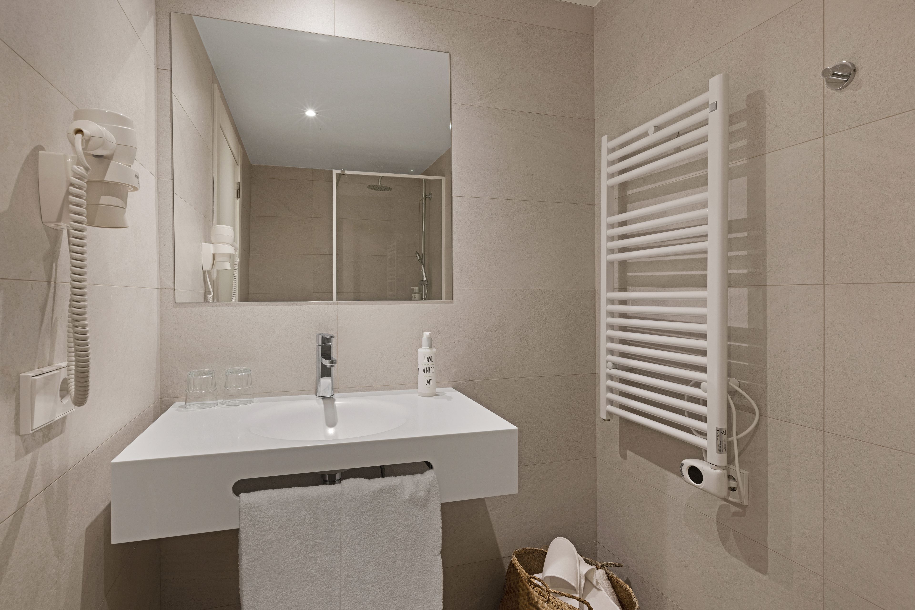 Un baño moderno con un lavabo blanco, espejo y toallero.