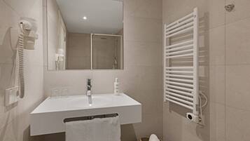 Un baño moderno con un lavabo blanco, espejo y toallero.