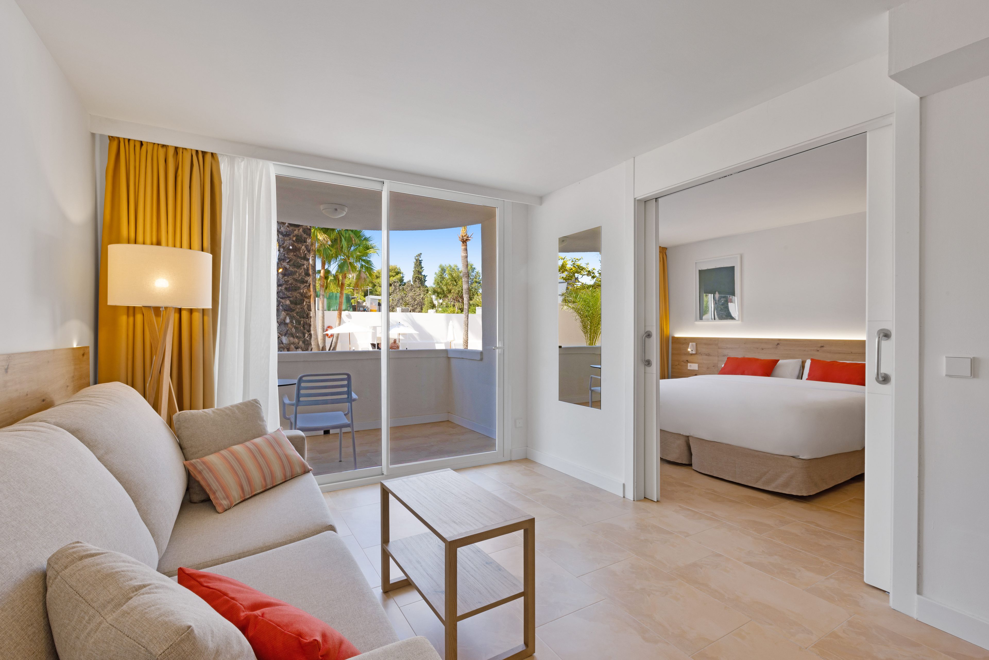 Una habitación de hotel moderna con balcón, cama, sofá y una pequeña mesa.