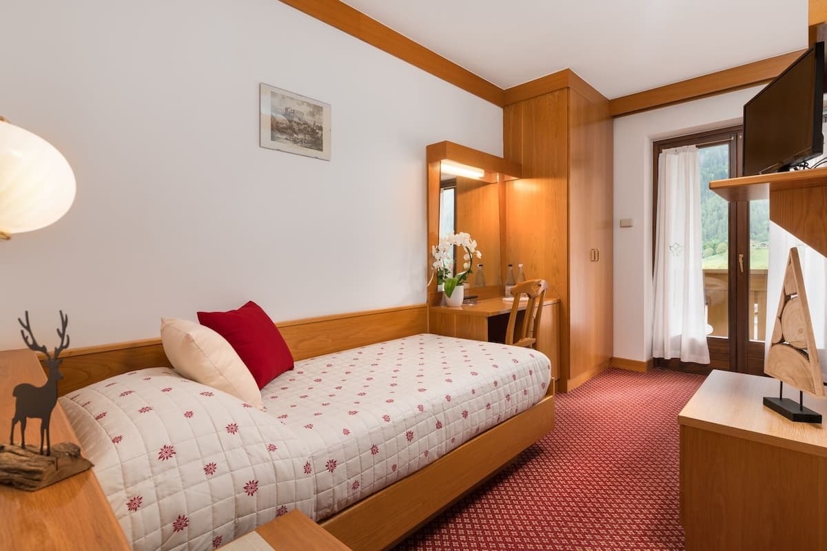 Ein gemütliches Zimmer mit Bett, Schreibtisch und Spiegel.