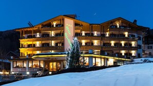 A multi-story hotel with balconies, a Christmas tree, and a snow-covered ground. - Hotel Bellavista (Giustino)