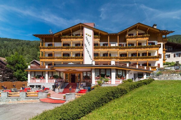 A multi-story hotel with balconies, a central entrance, and outdoor seating. - Hotel Bellavista (Giustino)
