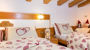 A hotel room with two beds, each with heart-patterned bedding, wooden headboards, and a night light.