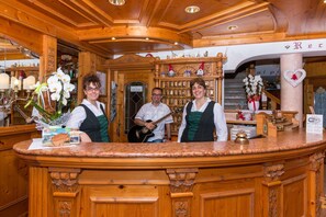A wooden reception desk with a marble top, surrounded by wooden paneling and a sign indicating WiFi availability. - Hotel Bellavista (Giustino)