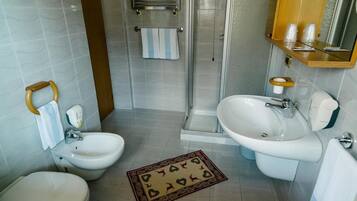 Une salle de bain avec deux lavabos, un bidet, une douche et des toilettes.