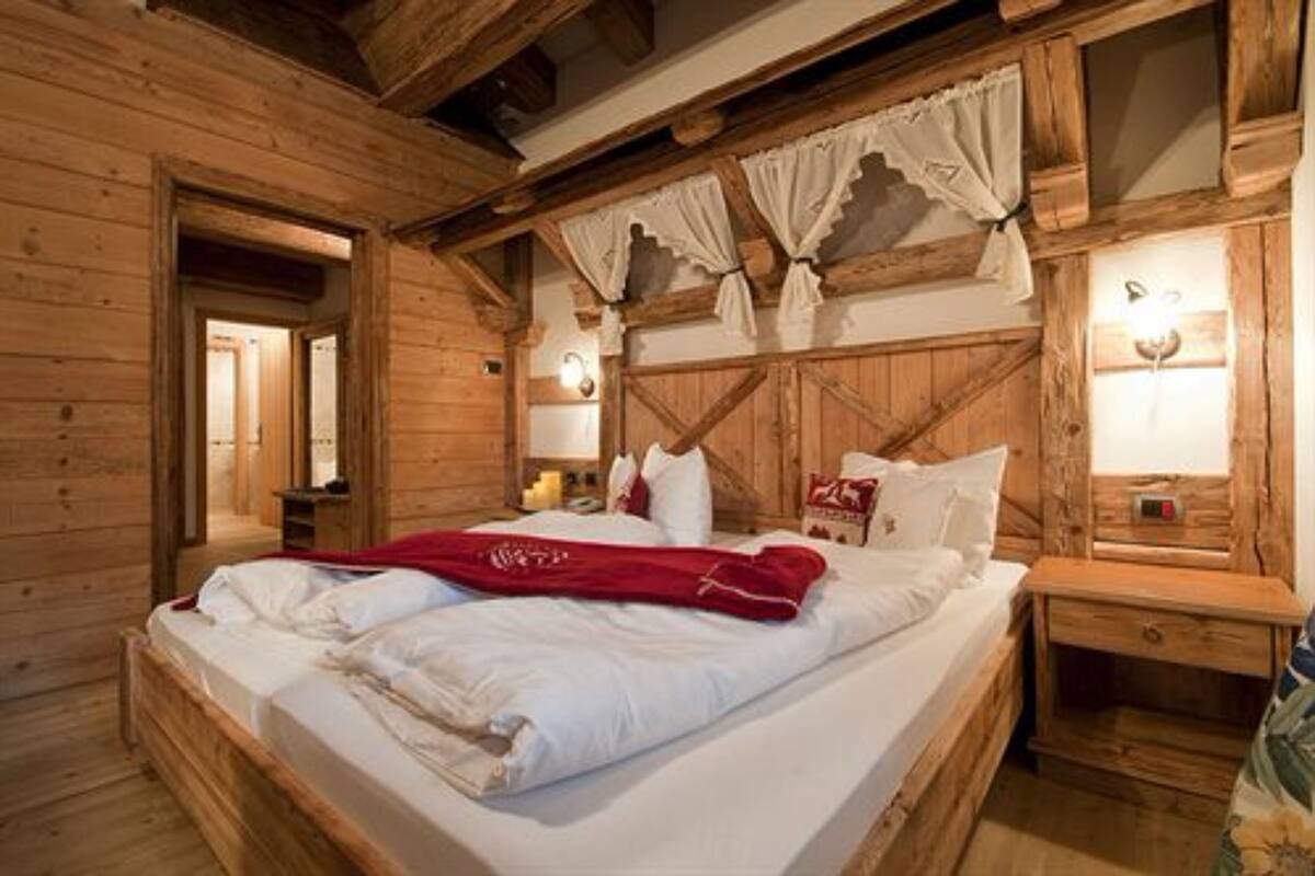 A wooden cabin-style bedroom with a bed, bedside tables, and a nightstand.