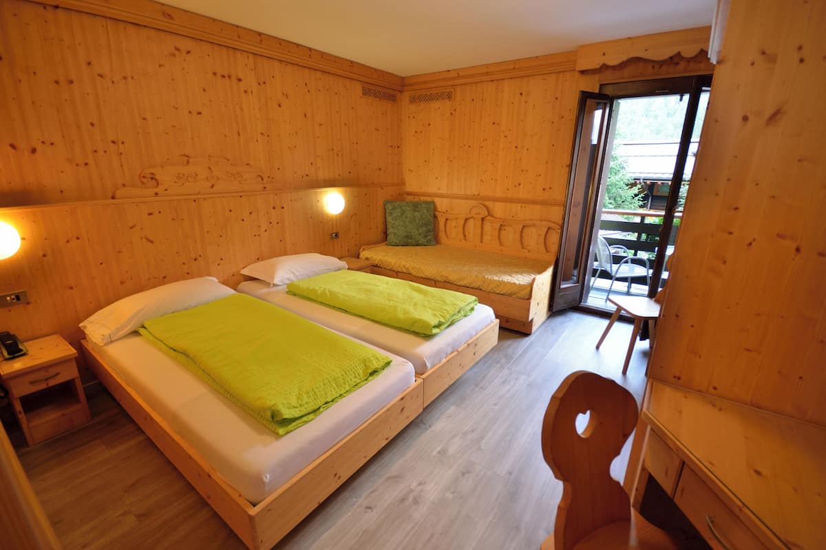 Una habitación de madera con dos camas, una mesita de noche, una silla y una pequeña mesa.