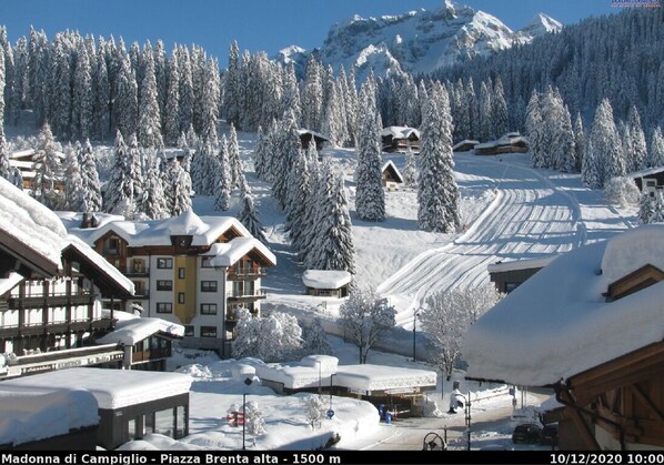 A snow-covered mountain village with wooden buildings and a ski slope. - Hotel Cime d'Oro (Pinzolo)